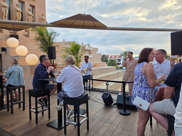 Gäste auf der Rooftop-Bar des Hard Rock Cafe Tenerife bei Livemusik in der Abenddämmerung.