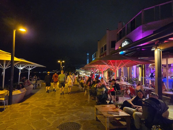 Abendliche Promenade mit Bars und Gästen in Playa de las Américas nahe dem Hard Rock Cafe.