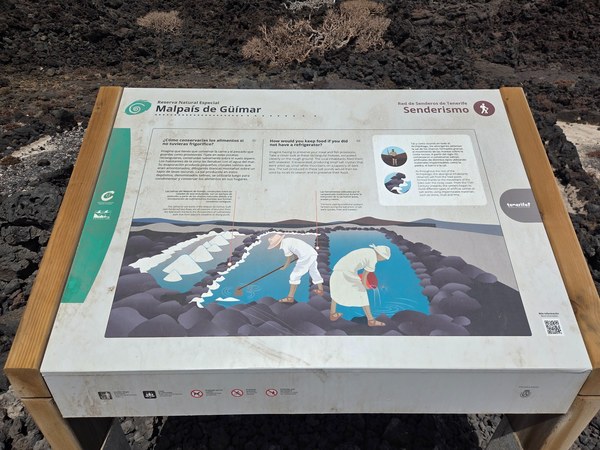 Infotafel im Malpaís de Güímar zur historischen Salzgewinnung mit Illustration von Salzbecken und Arbeitern.