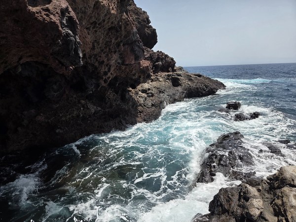 Gischt schlägt in eine von Lava geformte Bucht im Malpaís de Güímar; schwarzes Gestein kontrastiert mit türkisfarbenem Atlantik.