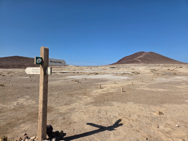 Wegweiser am Naturschutzgebiet: Abzweig zur Montaña Roja und zur Montaña Bocinegro über die Küstenebene.