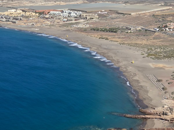 Weite Ansicht von der Playa de la Tejita mit goldbraunem Sand und sanfter Brandung.