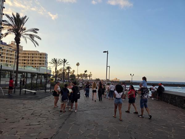 Menschen flanieren am frühen Abend die Promenade entlang zum Festbereich an der Playa Jardín.
