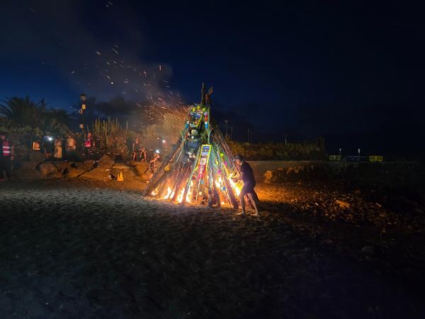 Ein Mann entzündet mit einer Fackel feierlich die San Juan Hoguera am Strand.