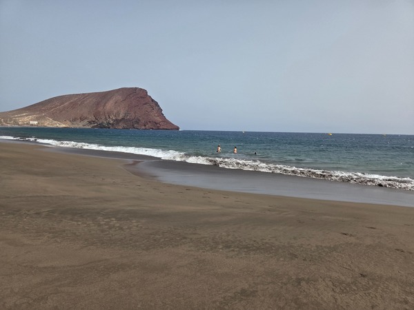 Weitwinkelaufnahme der Playa de La Tejita mit ruhiger Brandung und viel freier Fläche zum Spazieren.