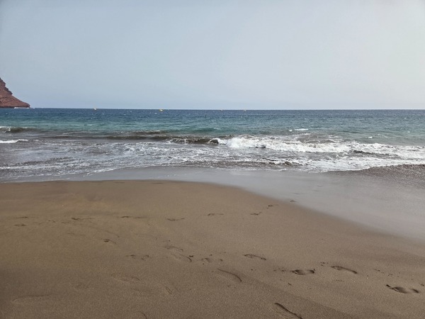 Brandung an der Playa de La Tejita mit nassen Sandflächen und unterschiedlichen Blautönen des Atlantiks.